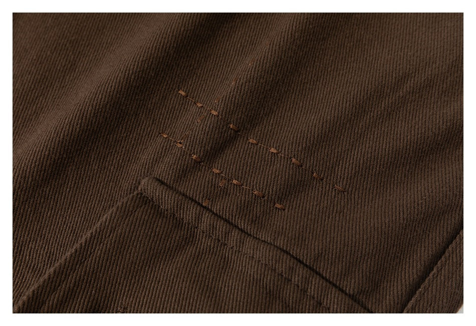 Close-up of brown trouser fabric with rows of stitching and a seam.
