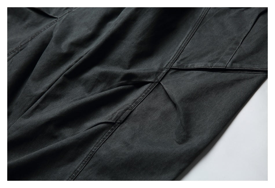 Close-up of charcoal pants showing angled seams and intersecting fabric panels.