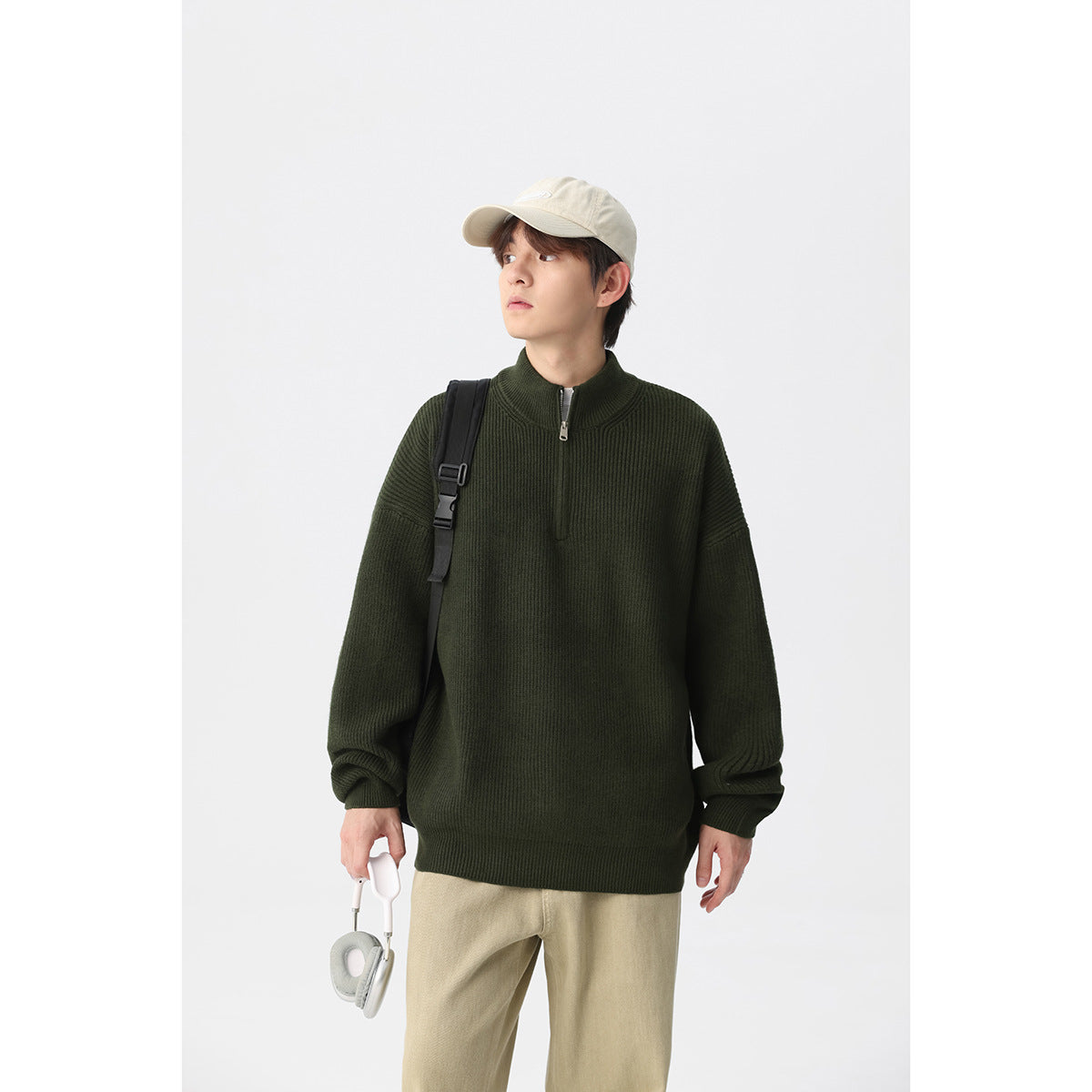Model wearing a dark olive ribbed quarter-zip sweater with a stand collar and dropped shoulders.