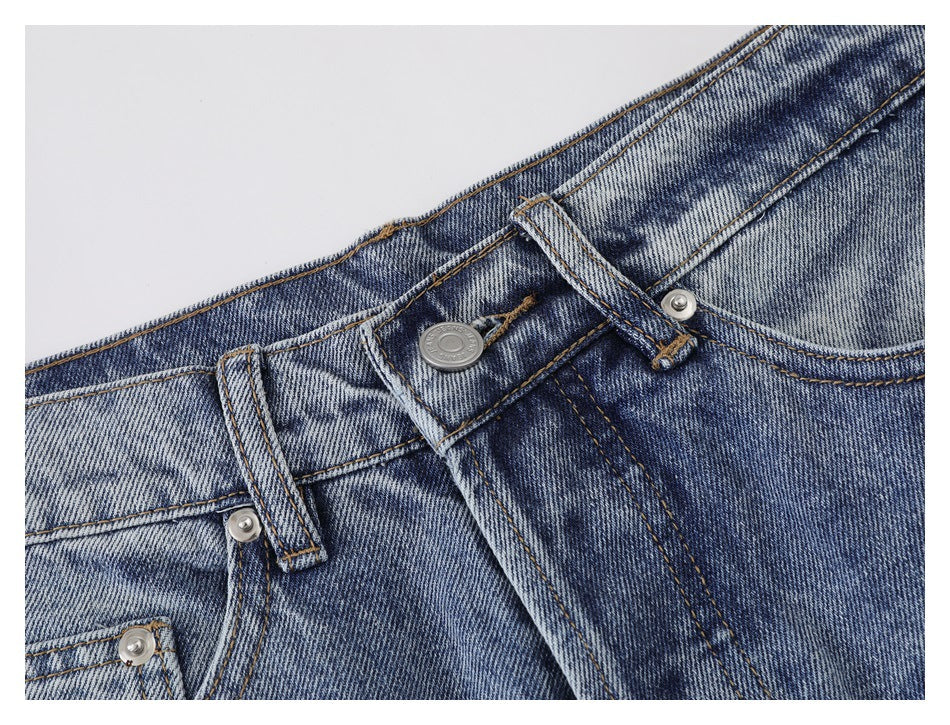 Close-up of the jeans' metal waist button, belt loops, fly stitching, and faded denim.
