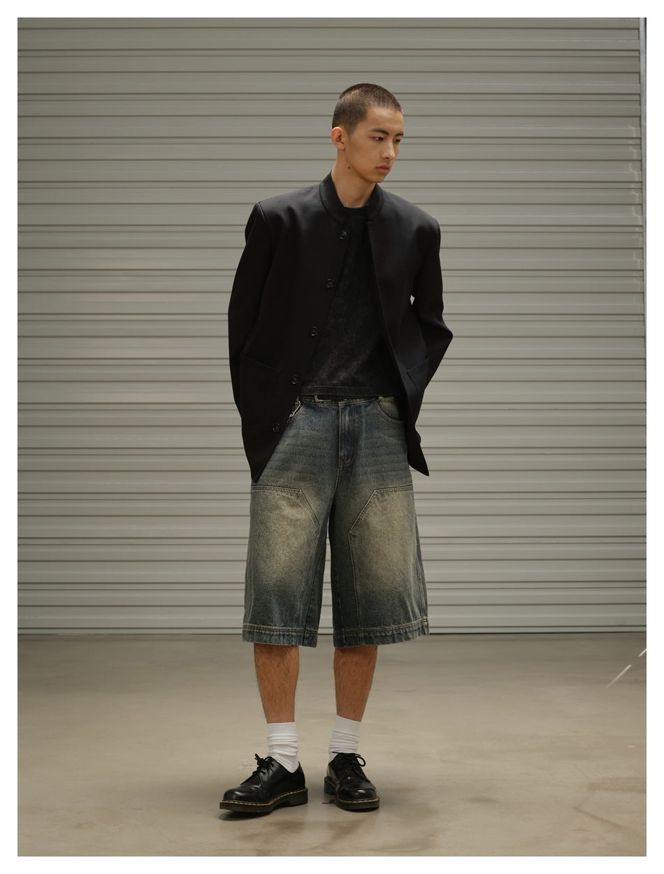 Model wearing a partly open black stand-collar jacket and loose faded denim shorts, shown at a slight angle.