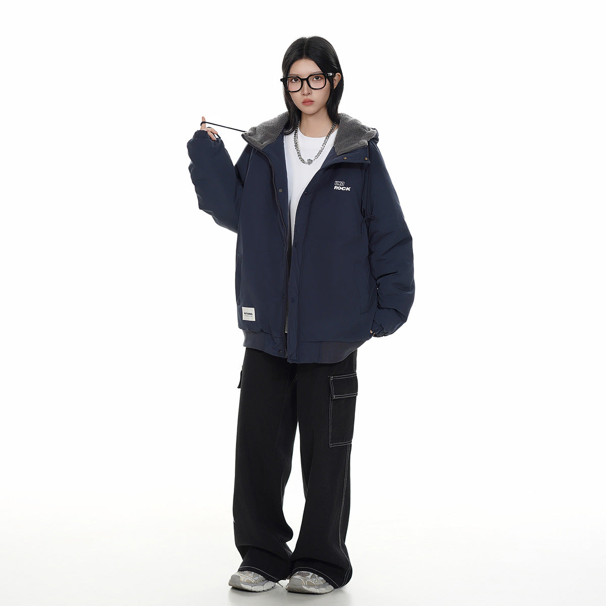 Model wearing an oversized navy hooded jacket with a gray fleece-lined collar, white shirt, and black wide-leg pants.
