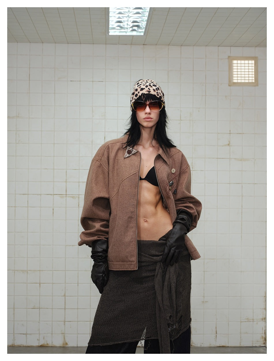 Model in oversized brown zip jacket worn open, showing dropped shoulders and button details, with black gloves