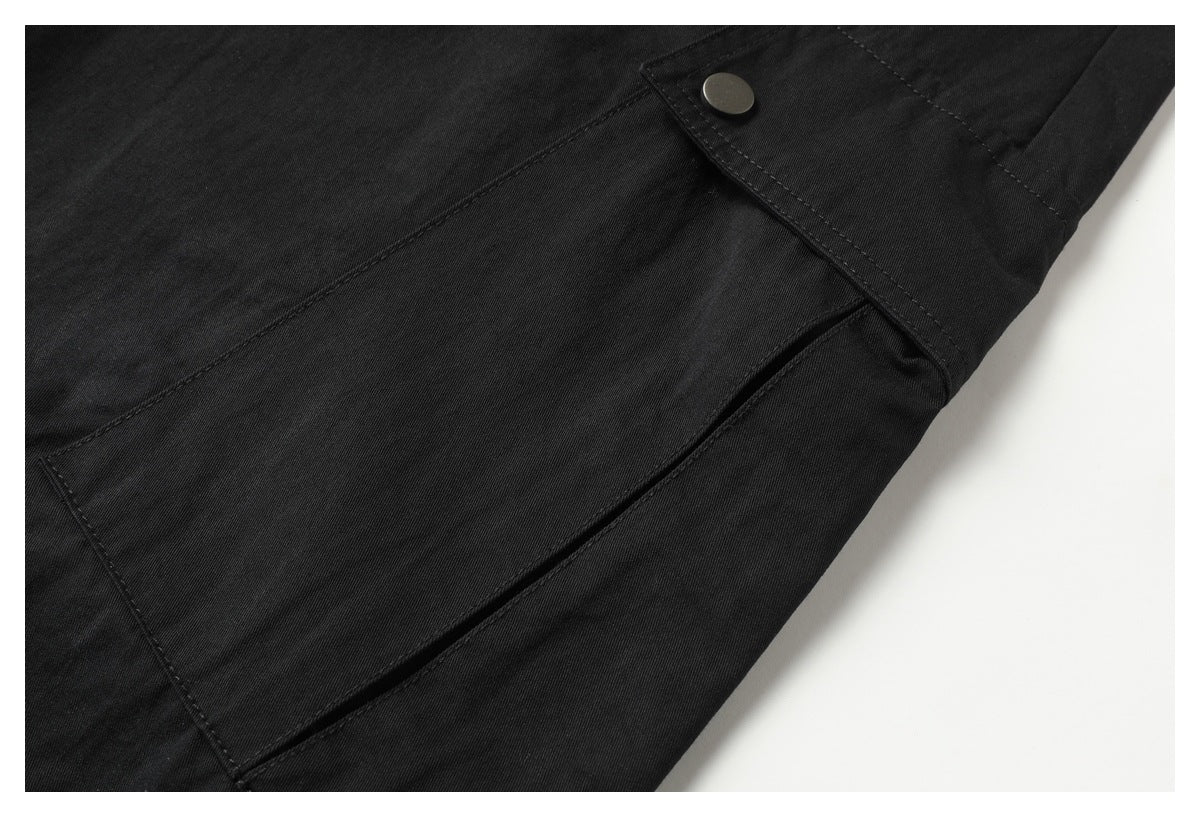 Close-up of a black cargo pocket flap with a round snap fastener and visible stitching.