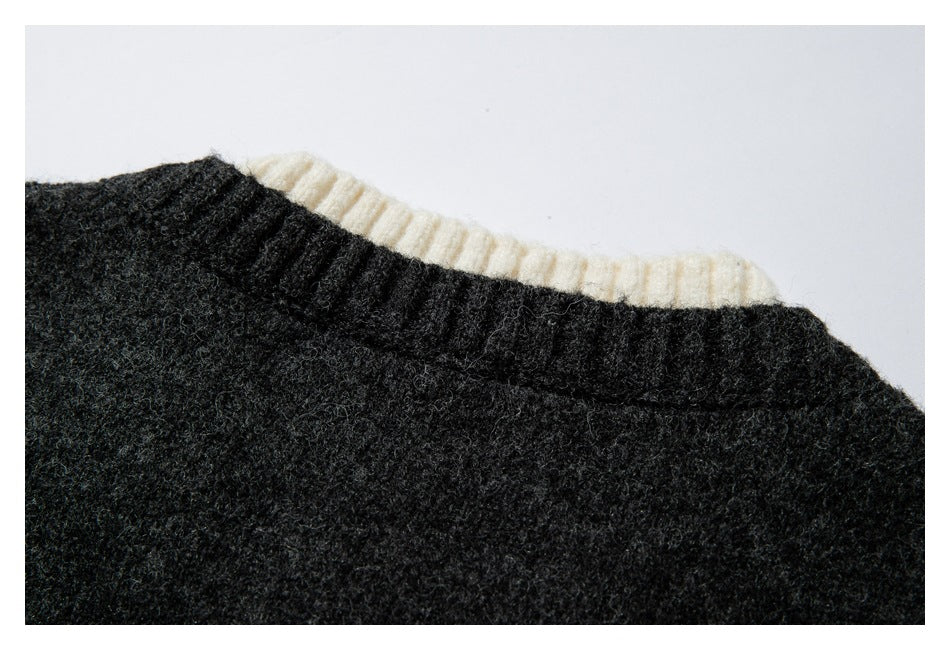 Close-up of the dark charcoal sweater neckline with cream ribbed trim visible behind it.