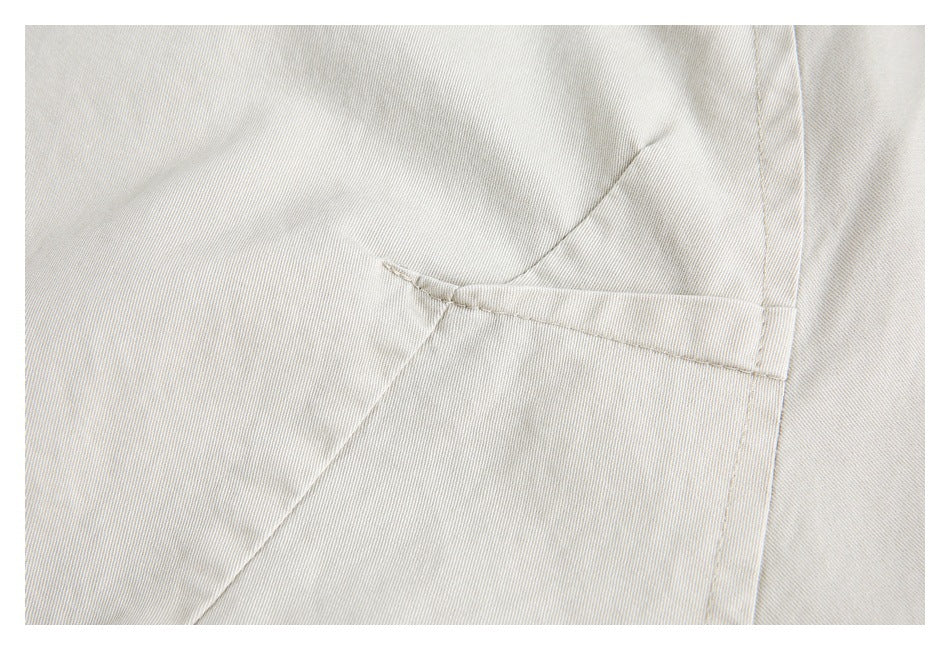 Close-up of cream fabric showing a narrow horizontal welt pocket and surrounding seams.