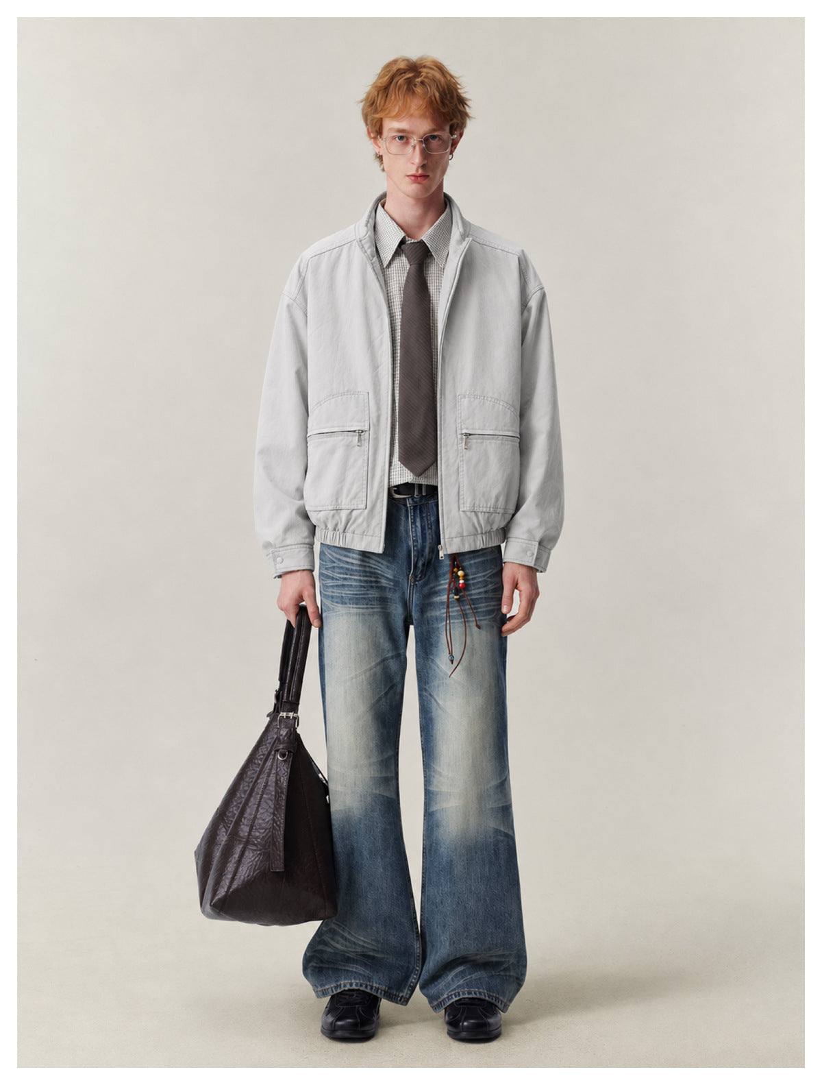 Model wearing a light gray zip-front jacket with a stand collar, large flap pockets, and elasticized hem.
