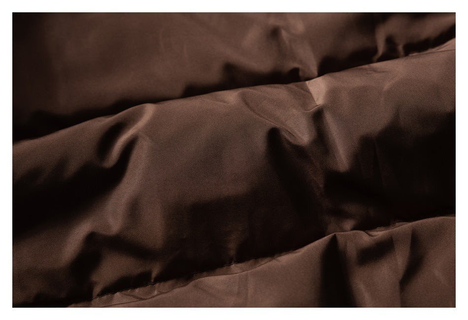 Close-up of smooth brown jacket fabric with folds and a stitched seam.