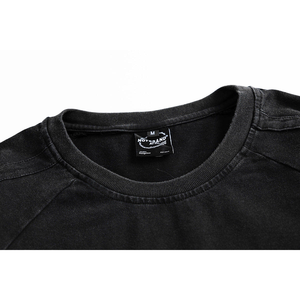Close-up of a black crew-neck T-shirt showing its ribbed collar, shoulder seams, and sewn neck label.
