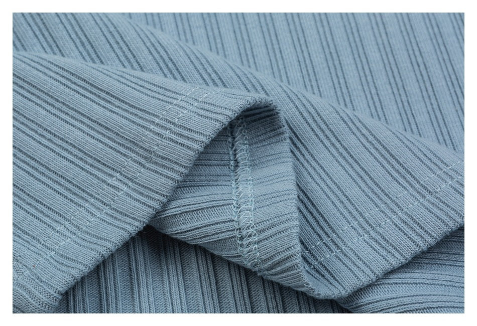 Close-up of the light blue ribbed top's folded hem and visible overlocked seam.