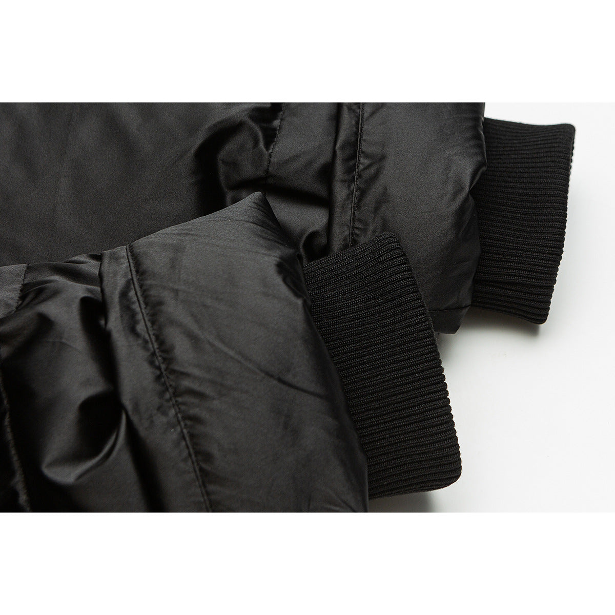 Close-up of a black padded jacket sleeve and wide ribbed cuff.