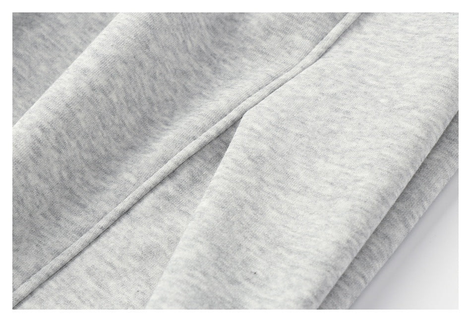 Close-up of light gray heathered sweatpants showing a diagonal stitched seam between fabric panels.