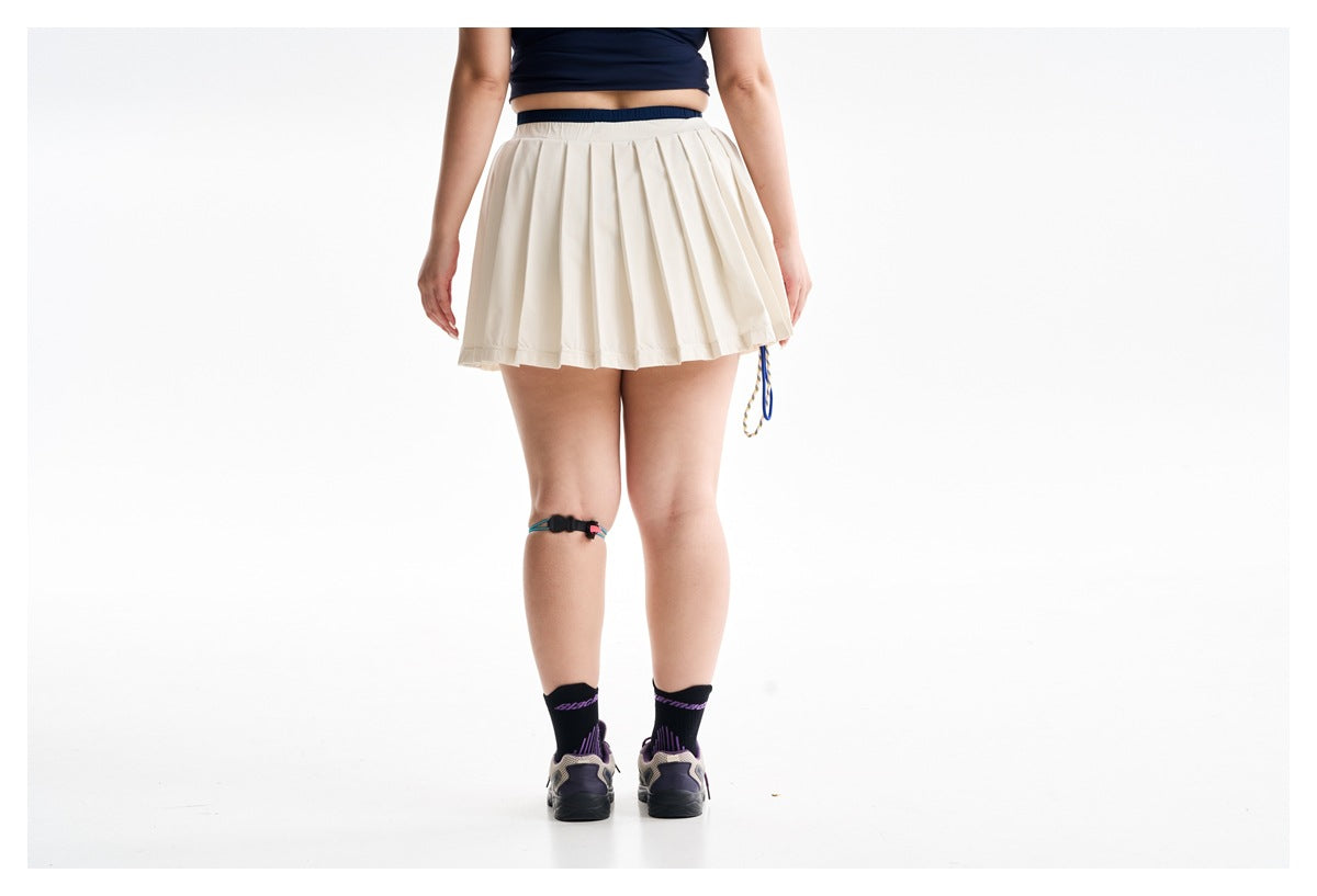 Rear view of a model wearing a cream pleated athletic skirt with a navy top.