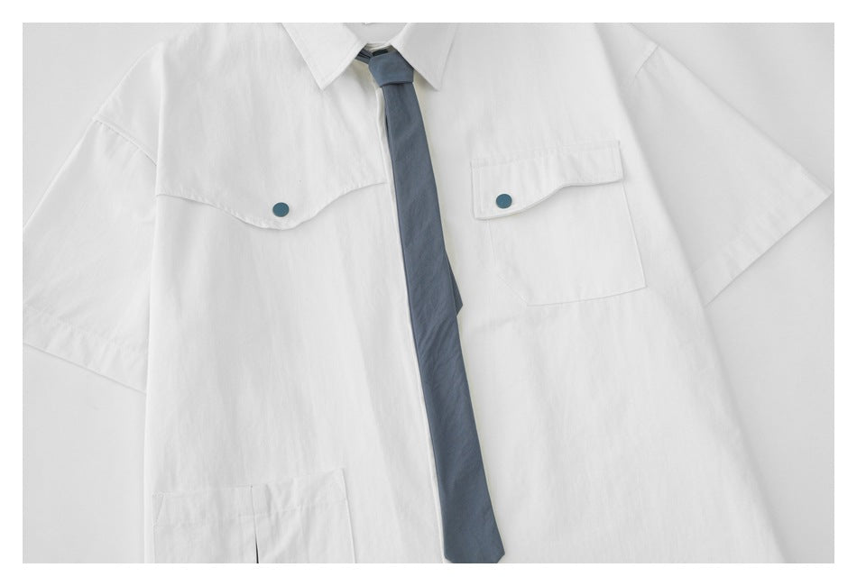 Close-up of the white shirt front with two flap pockets, teal buttons, and a blue tie.