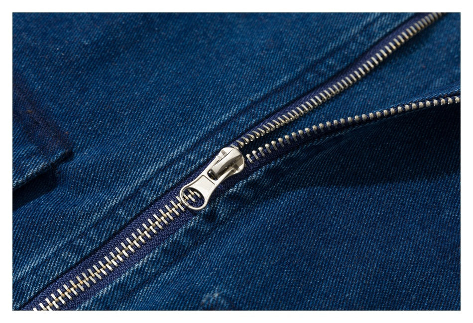 Close-up of a silver zipper and ring pull against dark blue denim.