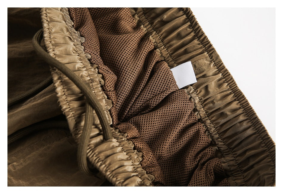 Close-up inside the brown trousers, showing brown mesh lining, the elastic waistband and a blank white tag.