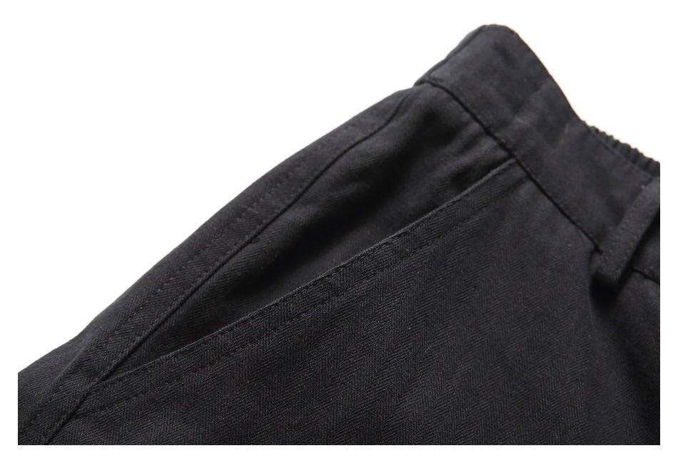 Close-up of a slanted pocket opening and waistband seam on black shorts.