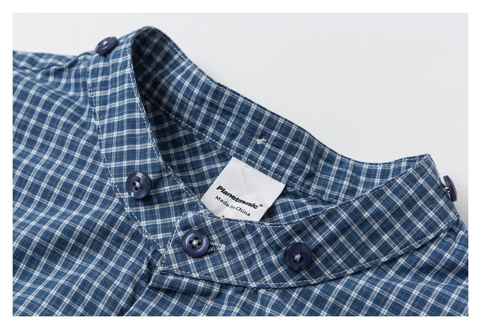 Close-up of a blue plaid shirt collar with dark buttons and a visible Planetmusic label.