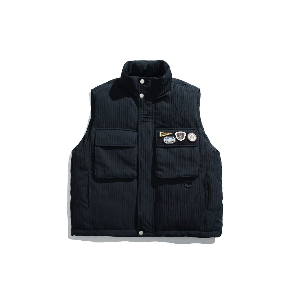 Black sleeveless vest with a high collar, snap-button front, two flap pockets, and decorative badges on the chest.