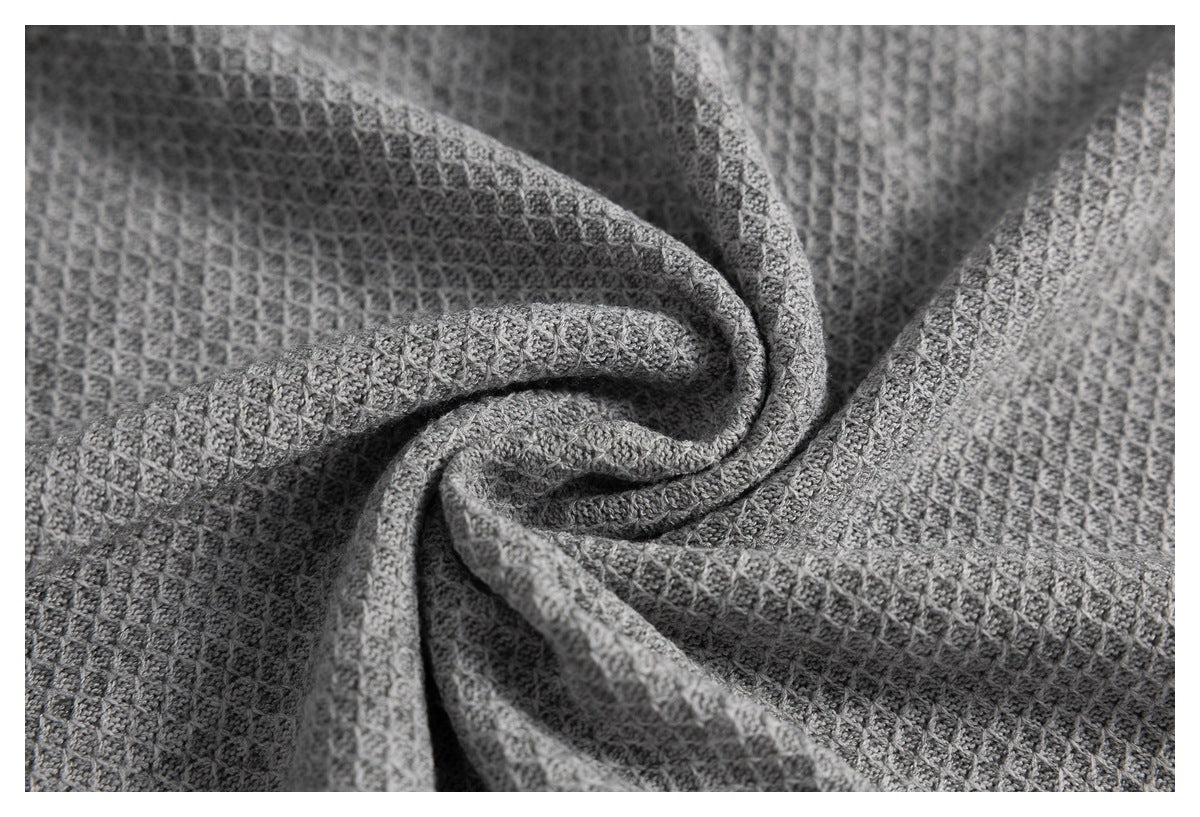 Close-up of gray fabric with a textured waffle knit pattern arranged in soft folds.