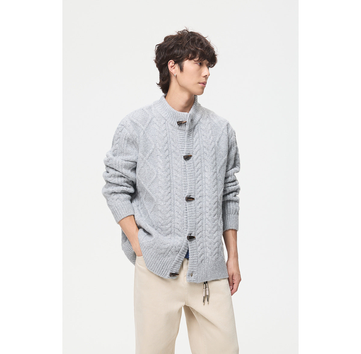 Model wearing a light gray cable-knit cardigan with a stand collar and toggle buttons, shown from the front.