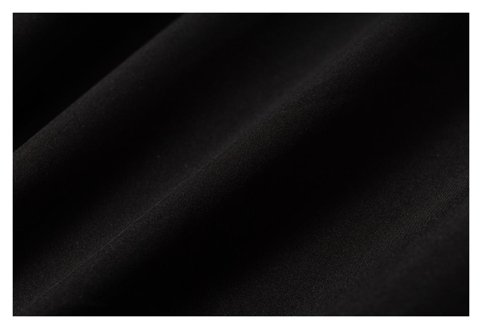 Close-up of black fabric showing a fine, subtle woven texture and soft diagonal folds.