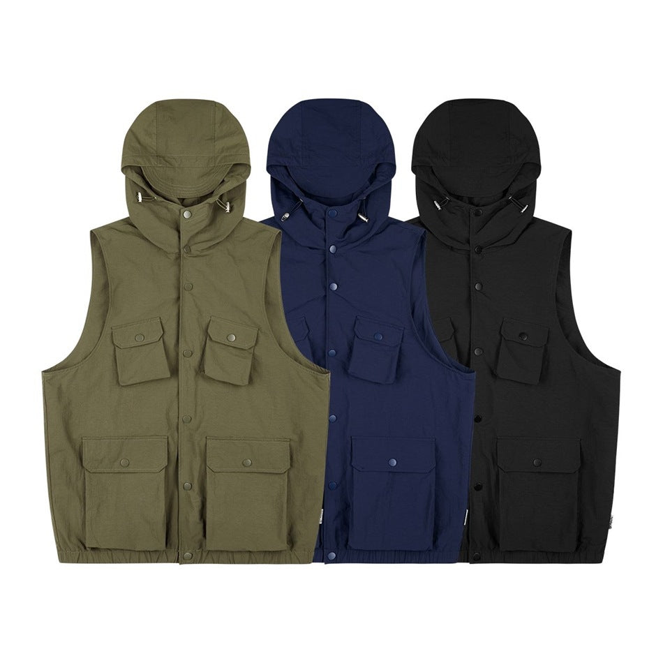 Three hooded utility vests shown from the front in olive, navy, and black, each with four flap pockets.