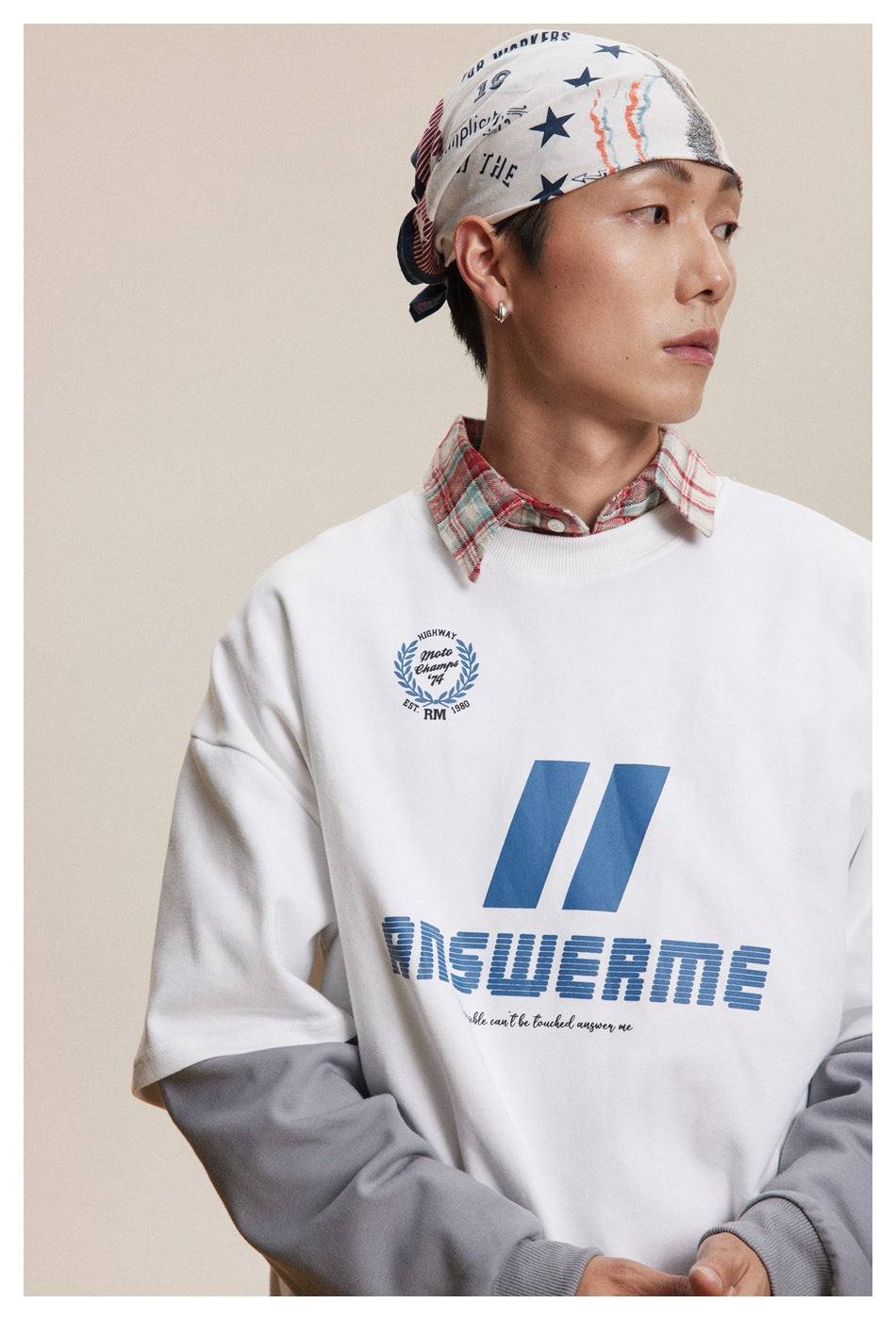 Close view of a model wearing a white sweatshirt with blue graphics and gray layered sleeves.