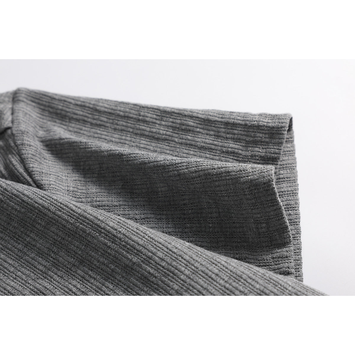 Close-up of gray ribbed T-shirt fabric and a folded stitched edge.
