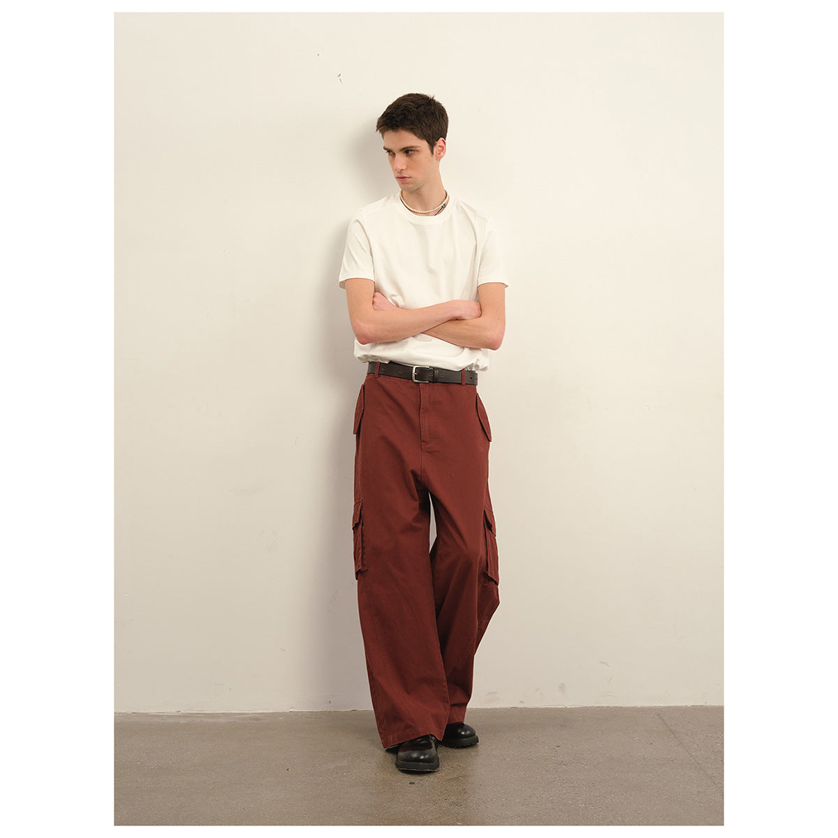 Model wearing a plain white T-shirt, rust-red wide-leg cargo trousers and black shoes.