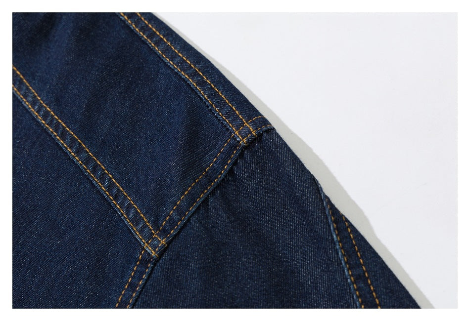 Close-up of dark indigo denim with curved panel seams and contrasting golden-orange stitching.