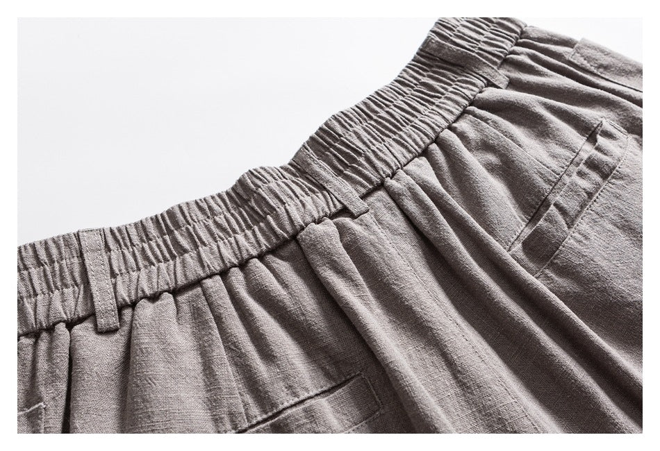 Close-up of light gray trousers with an elastic waistband, belt loops, and a rear pocket.