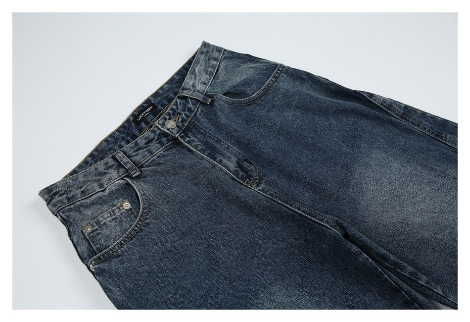 Angled close-up of the front waist and upper legs of dark blue washed jeans.