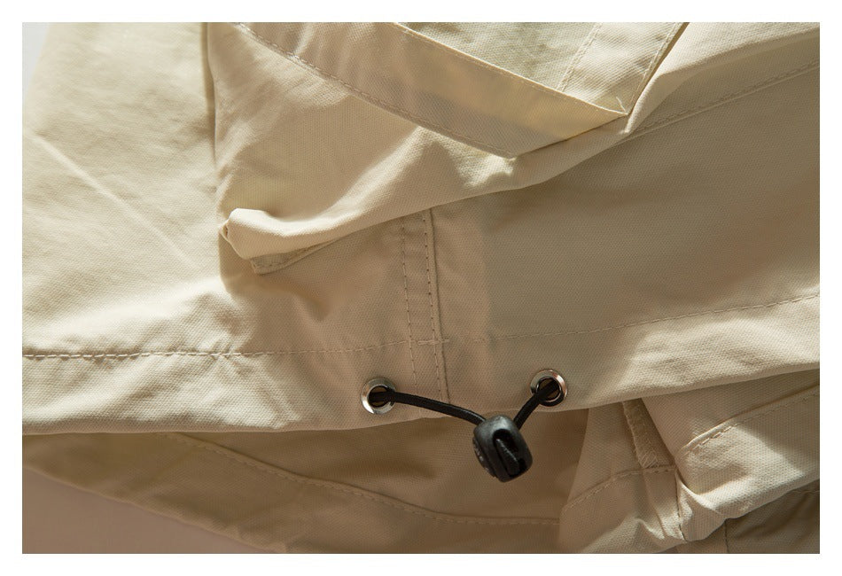 Close-up of the cream-beige garment hem with metal eyelets and a black drawcord toggle.