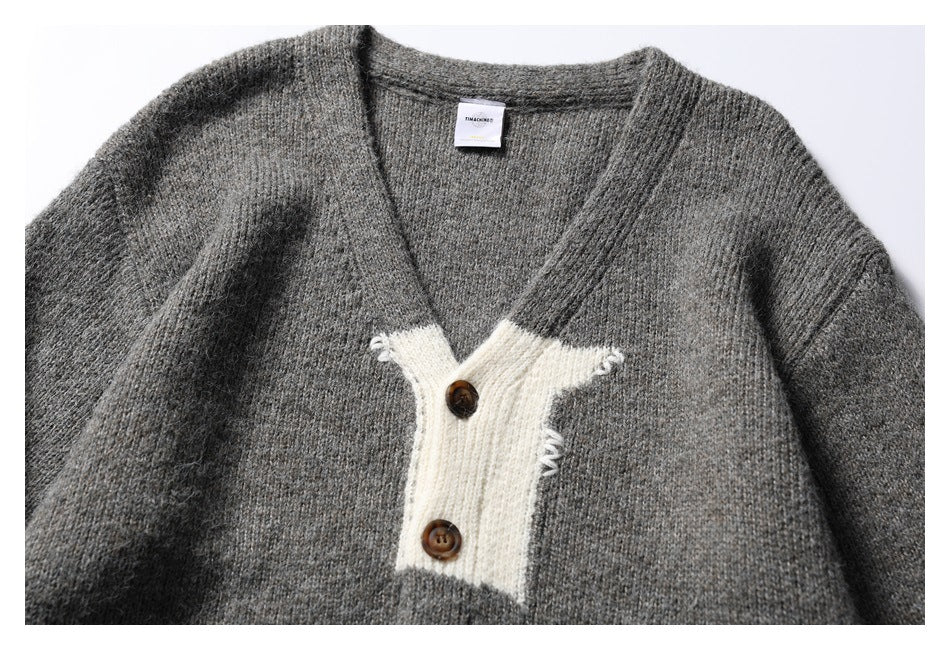 Close front view of a gray knit cardigan with a cream two-button placket and brown buttons.