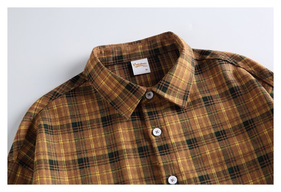 Close-up of the plaid shirt’s front collar and white-button placket, with a small label inside the neck.