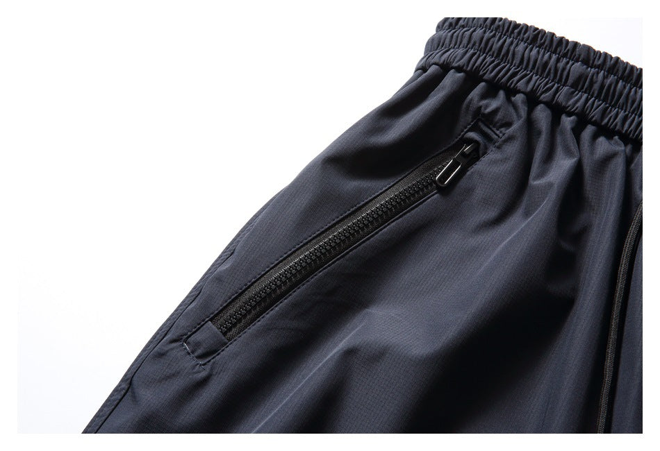 Close-up of a black zippered pocket on navy pants, beside the elastic waistband.