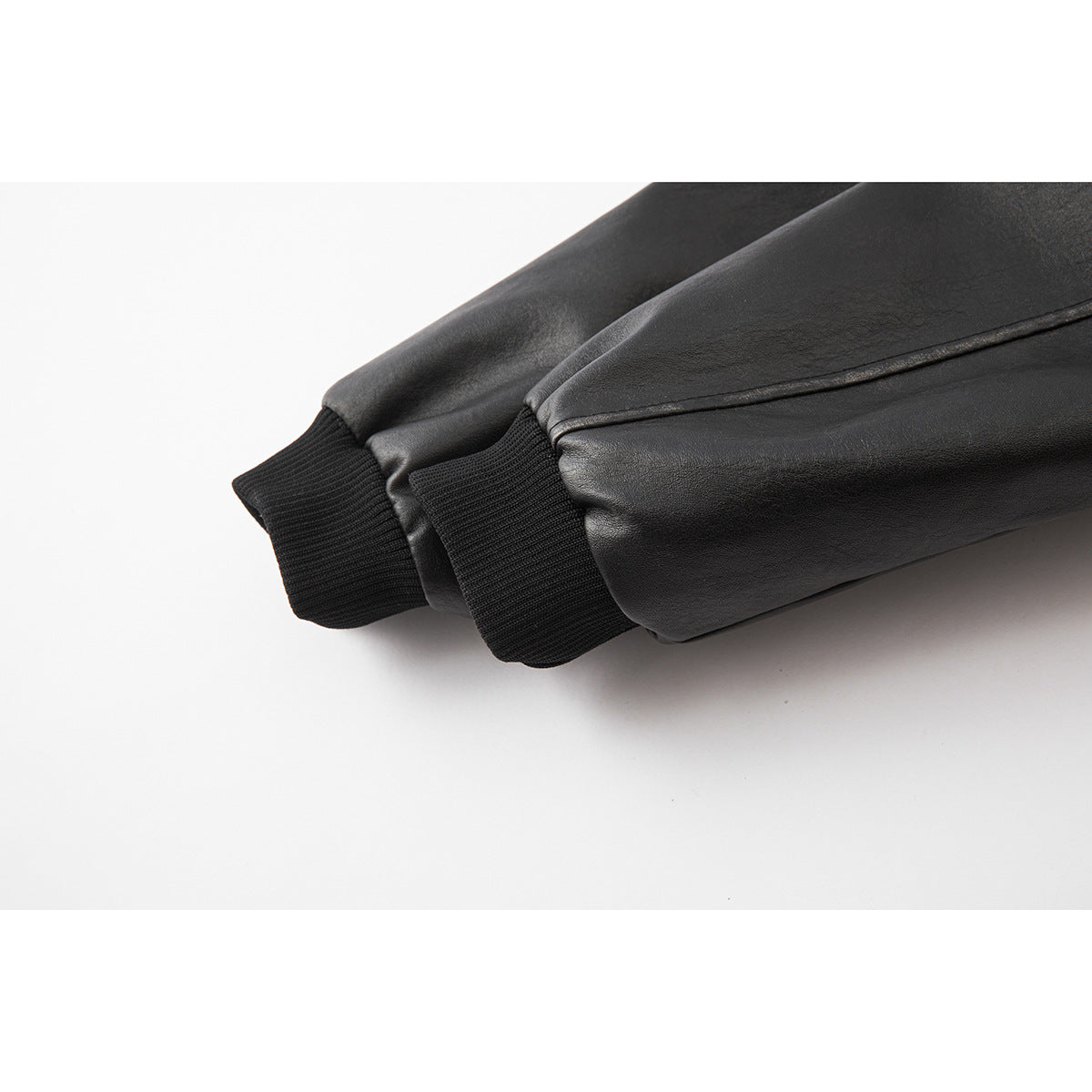 Close-up of black jacket sleeves ending in black ribbed cuffs.