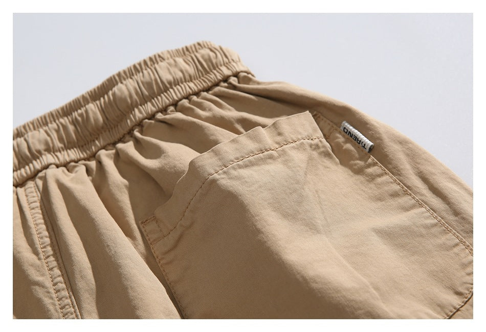 Close-up of tan shorts showing the elastic waistband, a large pocket, and a small sewn label.