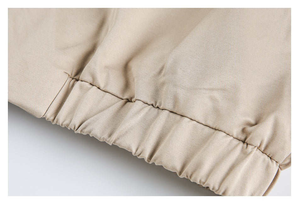 Close-up of the beige jacket's gathered elastic hem and stitching.