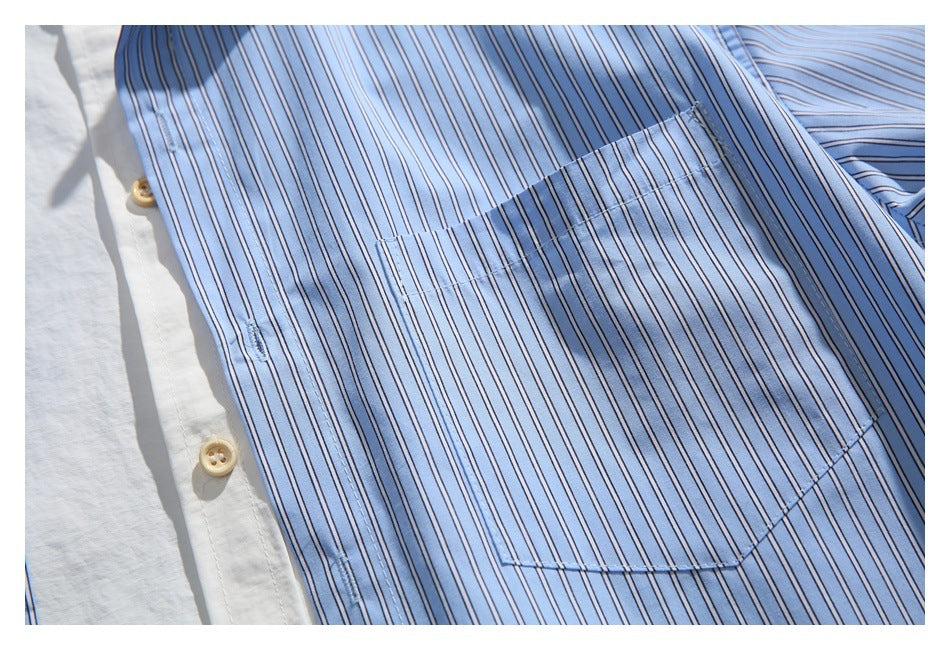 Close-up of a rectangular chest pocket on a light blue shirt with narrow dark stripes and tan buttons.
