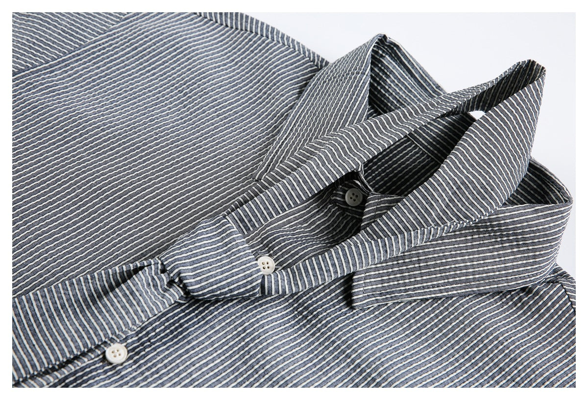 Close-up of the pointed collar and button placket on a navy and white striped shirt.
