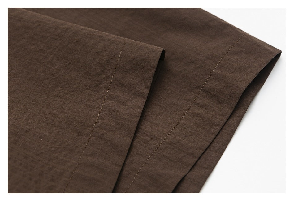 Close-up of the dark brown shirt's stitched sleeve cuff and hem area.
