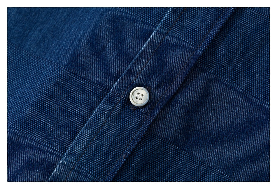 Close-up of a pale four-hole button on the navy shirt's textured fabric.