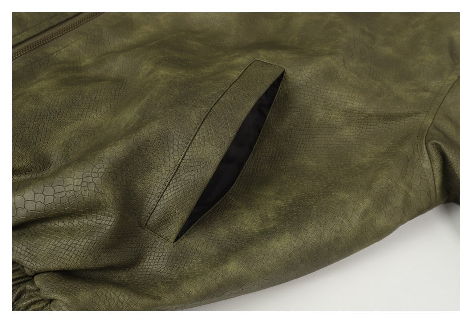 Close-up of an olive-green garment with a slanted welt pocket and subtle reptile-scale texture.