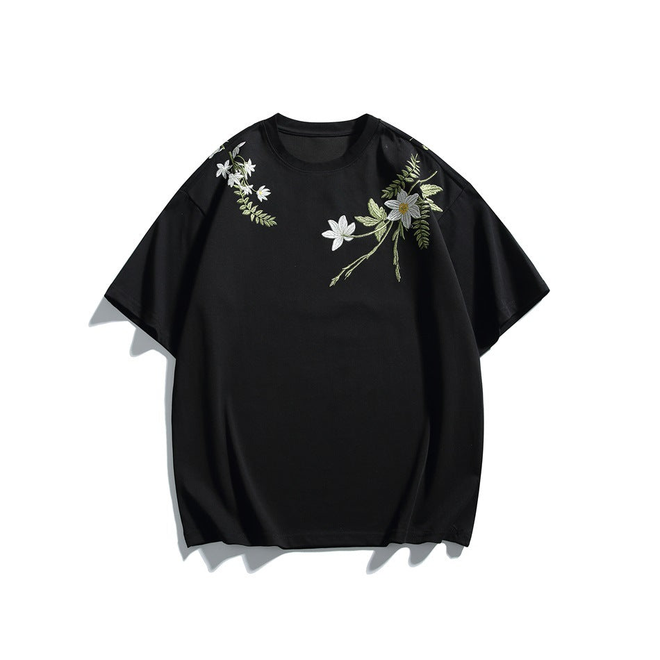 Black short-sleeve crew-neck T-shirt with green leaf and white flower embroidery on the shoulders, front view