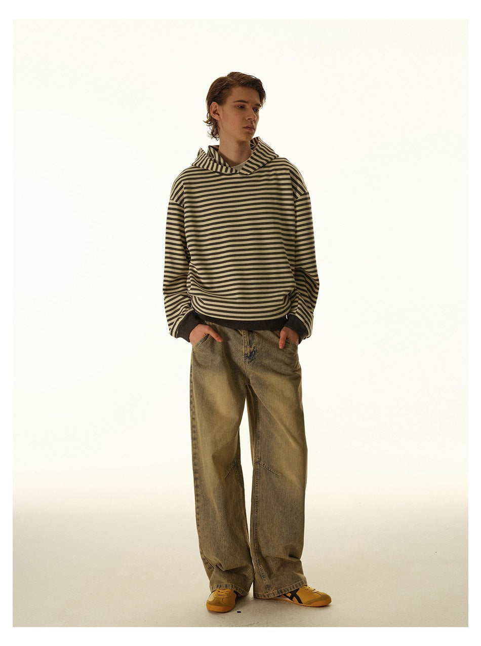Full-length view of a model in a striped hoodie, wide-leg washed jeans and yellow sneakers, hands in pockets
