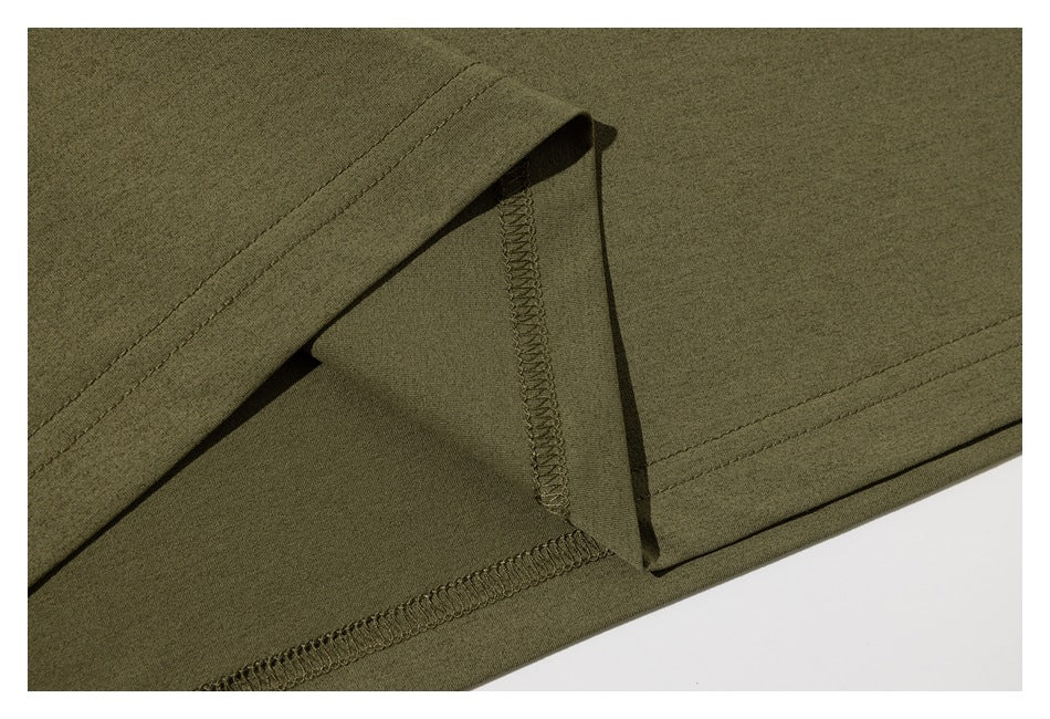 Close-up of an olive-green garment hem showing the folded edge and overlocked seam.