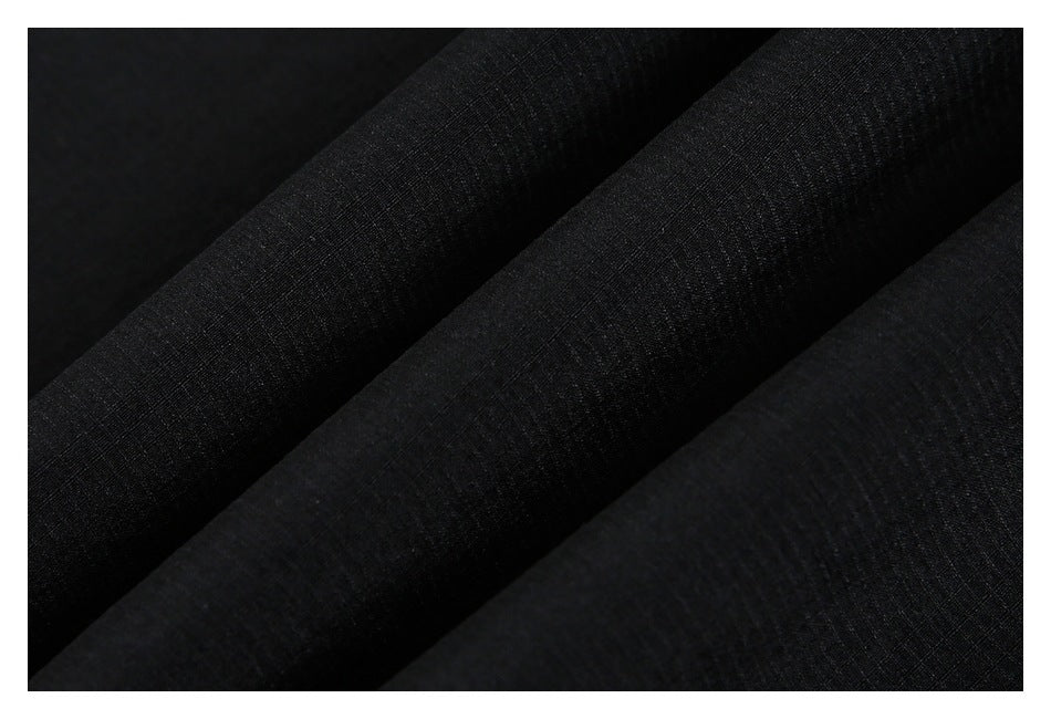 Close-up of black fabric arranged in soft folds, showing its subtle textured surface.