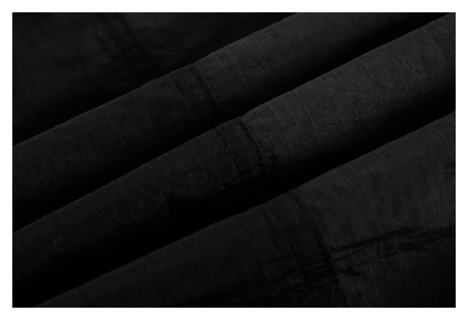 Extreme close-up of black fabric showing its subtle grid texture and stitched folds.